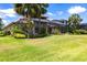A spacious backyard featuring a large screened-in lanai, lush green grass, and palm trees at 5502 Tidewater Preserve Blvd, Bradenton, FL 34208