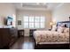 Comfortable bedroom with a tray ceiling, wood flooring, and large windows with plantation shutters at 5502 Tidewater Preserve Blvd, Bradenton, FL 34208
