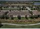 Aerial view of condo complex with tile roofs near a pond, golf course, and suburban homes in the background at 5528 Palmer Cir # 204, Lakewood Ranch, FL 34211