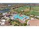 Vibrant aerial view of the community pool with a bridge and waterfall feature with surrounding palm trees at 5528 Palmer Cir # 204, Lakewood Ranch, FL 34211