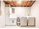 Laundry area features modern washer, dryer, utility sink, ample cabinet space, and exposed wood ceiling at 6009 Lords Ave, Sarasota, FL 34231