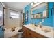 Charming bathroom with blue walls, a wood vanity, a framed mirror, and a shower-tub combo at 610 Poinsettia Rd, Nokomis, FL 34275