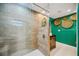 Modern bathroom with a glass-enclosed shower, wood-look tile, and green walls accented by decorative baskets at 610 Poinsettia Rd, Nokomis, FL 34275