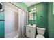 Green bathroom featuring a shower-tub combination and white vanity for a clean, classic look at 610 Poinsettia Rd, Nokomis, FL 34275