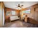 Wood-paneled bedroom with a ceiling fan, desk, and futon, providing a warm and inviting space at 610 Poinsettia Rd, Nokomis, FL 34275