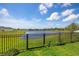 Scenic backyard view features a tranquil lake, bordered by a black fence and lush green lawn at 7322 34Th E Ct, Sarasota, FL 34243