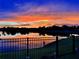Beautiful sunset reflecting off of pond with black metal fence in foreground at 7322 34Th E Ct, Sarasota, FL 34243