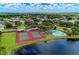 Aerial view showcasing community tennis courts, pool, and serene lake, surrounded by lush greenery at 7814 48Th E Ave, Bradenton, FL 34203