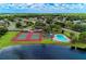 Aerial view showcasing community tennis courts, pool, and serene lake, surrounded by lush greenery at 7814 48Th E Ave, Bradenton, FL 34203