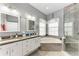 Bathroom featuring double sinks, granite countertops, large soaking tub and walk-in shower with glass door at 7814 48Th E Ave, Bradenton, FL 34203