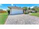 Paver driveway leads to a two-car garage of a one-story home with attractive landscaping at 7814 48Th E Ave, Bradenton, FL 34203