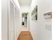 Bright hallway featuring hardwood floors, closet doors, and artwork leading to an open bathroom at 7814 48Th E Ave, Bradenton, FL 34203