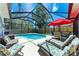 Relaxing screened-in pool area with colorful furniture and a red umbrella for shade on a sunny day at 7814 48Th E Ave, Bradenton, FL 34203
