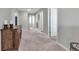 Neutral-toned hallway with carpet and an antique wood dresser, leading to various rooms in the home at 8346 Abalone Loop, Parrish, FL 34219