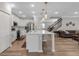 Open-concept kitchen boasts white cabinets, stainless steel appliances, a large island, and stylish pendant lighting at 8346 Abalone Loop, Parrish, FL 34219