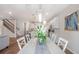Bright dining area with an elegant light fixture, white table, and chairs, seamlessly connecting to the open kitchen and living area at 9095 Rally Spring Loop, Wesley Chapel, FL 33545