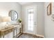 Elegant foyer featuring a decorative glass door, stylish console table with a lamp, and a round mirror, creating a welcoming entrance at 9095 Rally Spring Loop, Wesley Chapel, FL 33545