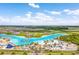 Aerial view of a vibrant community lagoon featuring sandy beaches, clear turquoise waters, and recreational activities at 9095 Rally Spring Loop, Wesley Chapel, FL 33545