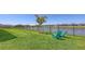 Large backyard with green lawn, a black fence, direct access to a serene pond, and two chairs at 11869 Richmond Trl, Parrish, FL 34219