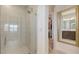 A glass-enclosed shower is next to a mirror reflecting the walk-in closet and bathroom sink at 11869 Richmond Trl, Parrish, FL 34219