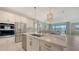 Modern kitchen features white cabinetry, stainless steel appliances and center island with quartz countertop and gold accents at 11869 Richmond Trl, Parrish, FL 34219