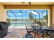 Covered patio with black metal table set, ceiling fan and a view of the pool and lake at 12501 Cinqueterre Dr, Venice, FL 34293