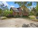 Charming two-story red house with a welcoming front porch and a lush green lawn with mature trees at 14514 20Th E St, Parrish, FL 34219
