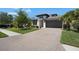 Charming front exterior with a brick paver driveway, lush landscaping, and a modern architectural design at 14514 20Th E St, Parrish, FL 34219