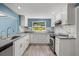 Bright kitchen features stainless steel appliances, gray countertops, light blue accent wall and white cabinets at 1518 Stoeber Ave, Sarasota, FL 34232