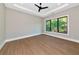Bright bedroom features wood floors, a tray ceiling with a modern fan, and a large window with a garden view at 1555 Eastbrook Dr, Sarasota, FL 34231