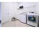 Bright laundry room featuring a washing machine, dryer, sink and cabinet with neutral tile floors at 16848 Rosedown Gln, Parrish, FL 34219