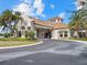 Elegant clubhouse exterior with a porte cochere, stone accents, beautiful landscaping, and a circular driveway at 17902 Gawthrop Dr # 107, Bradenton, FL 34211