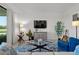 Cozy living room with a blue accent chair, patterned rug, modern glass coffee table, and views of the outside golf course at 17902 Gawthrop Dr # 107, Bradenton, FL 34211