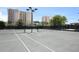 Tennis court with lighting in front of highrise condos and tropical foliage at 1800 Benjamin Franklin Dr # B310, Sarasota, FL 34236