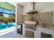 Covered outdoor kitchen with a stainless steel grill, granite countertops, and a pool view at 1842 Kenilworth St, Sarasota, FL 34231