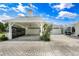 Exterior view of a charming home with a carport, lush landscaping, and a light-colored brick driveway at 1907 4Th W St, Palmetto, FL 34221