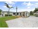 Bright waterfront home with a spacious deck, covered porch, manicured lawn, and pristine white gravel driveway at 1907 4Th W St, Palmetto, FL 34221