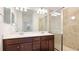 A stylish bathroom featuring double sinks, a large mirror, and tiled shower with glass doors at 20398 Lagente Cir, Venice, FL 34293