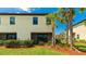 Back exterior of home showing an enclosed lanai, lush lawn, and mature palm trees at 20398 Lagente Cir, Venice, FL 34293