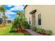 Charming home exterior featuring a well-manicured lawn, palm trees, and a welcoming entryway at 20398 Lagente Cir, Venice, FL 34293