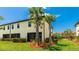 Inviting townhouse with a screened patio and vibrant landscaping, including palm trees on a sunny day at 20398 Lagente Cir, Venice, FL 34293