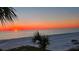 Stunning sunset view over the ocean with palm trees in the foreground on a wide sandy beach at 2301 Gulf Of Mexico Dr # 36N, Longboat Key, FL 34228