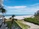 Expansive beach view from a condo balcony, overlooking white sands, azure waters, and swaying palm trees at 2301 Gulf Of Mexico Dr # 36N, Longboat Key, FL 34228