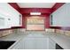 Charming kitchen featuring white cabinets, red accent wall, and a window over the sink at 2609 Webber St, Sarasota, FL 34239