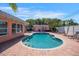 Sparkling pool and brick paver patio surrounded by lush tropical landscaping with lounge chairs at 2609 Webber St, Sarasota, FL 34239