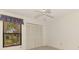 A clean bedroom with neutral walls, featuring a ceiling fan and a window with a view at 314 Pembroke Ln # 189, Venice, FL 34293