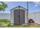 Outdoor storage shed with gray double doors, situated in a fenced backyard at 322 Linden Dr, Ellenton, FL 34222