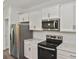 Kitchen view with stainless steel refrigerator and microwave and white cabinets at 3812 Wenona Dr, North Port, FL 34288