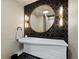 Modern bathroom features unique backsplash, floating sink, and round mirror with sconces at 415 L Ambiance Dr # D306, Longboat Key, FL 34228