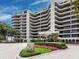 Elegant condo building featuring curved balconies, lush landscaping, and a welcoming entrance at 415 L Ambiance Dr # D306, Longboat Key, FL 34228